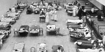 FILE - In this 1918 photo made available by the Library of Congress, volunteer nurses from the American Red Cross tend to influenza patients in the Oakland Municipal Auditorium, used as a temporary hospital. (Edward A. "Doc" Rogers/Library of Congress via AP, File)