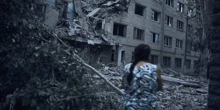 A Ukrainian woman walks amid the debris of a residential building following night shelling in Mykolaiv, Ukraine, Tuesday, Aug. 2, 2022. (AP Photo/Kostiantyn Liberov)