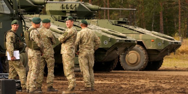Lithuanian army servicemen gather next to the infantry fighting vehicles Vilkas during presentation in Pabrade military field, Lithuania September 6, 2022. Vilkas infantry fighting vehicles (IFVs) have been made by a German manufacturer ARTEC, according to the requirements of the Lithuanian Land Force. Vilkas are Boxer-based and equipped with Israeli-made turrets, US-made 30 mm MK-44S cannons and Israeli-made anti-armor Spike LR missiles. REUTERS/Ints Kalnins