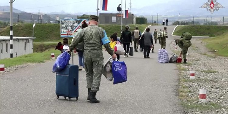 In this photo taken from a video released by Russian Defense Ministry Press Service on Thursday, Sept. 21, 2023, Russian peacekeepers help ethnic Armenians to get a camp near Stepanakert in Nagorno-Karabakh. Thousands of Nagorno-Karabakh residents flocked to a camp operated by Russian peacekeepers to avoid the fighting, while many others gathered at the airport of the regional capital, Stepanakert, hoping to flee the region. (Russian Defense Ministry Press Service via AP)